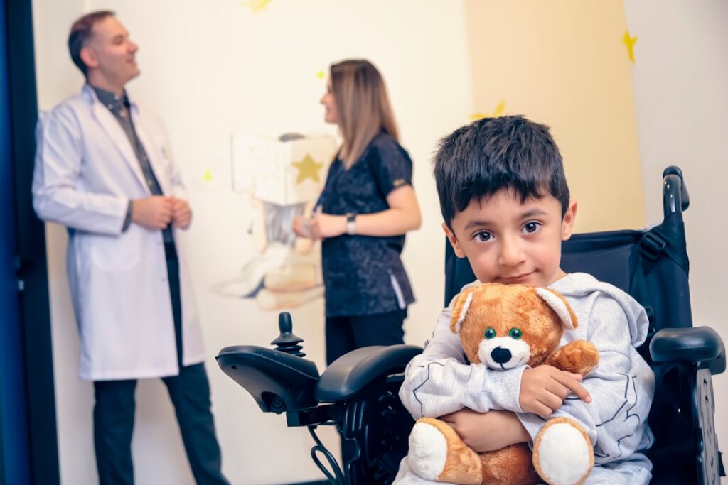 a boy in a wheelchair holding a teddy bear