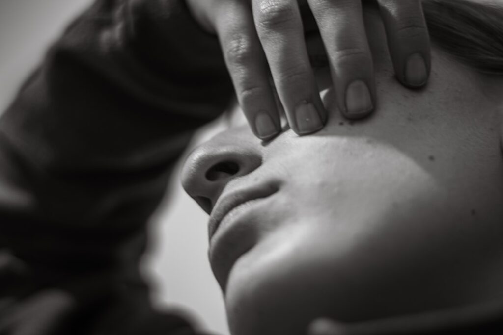 Close-up of a person's face with hand covering eye