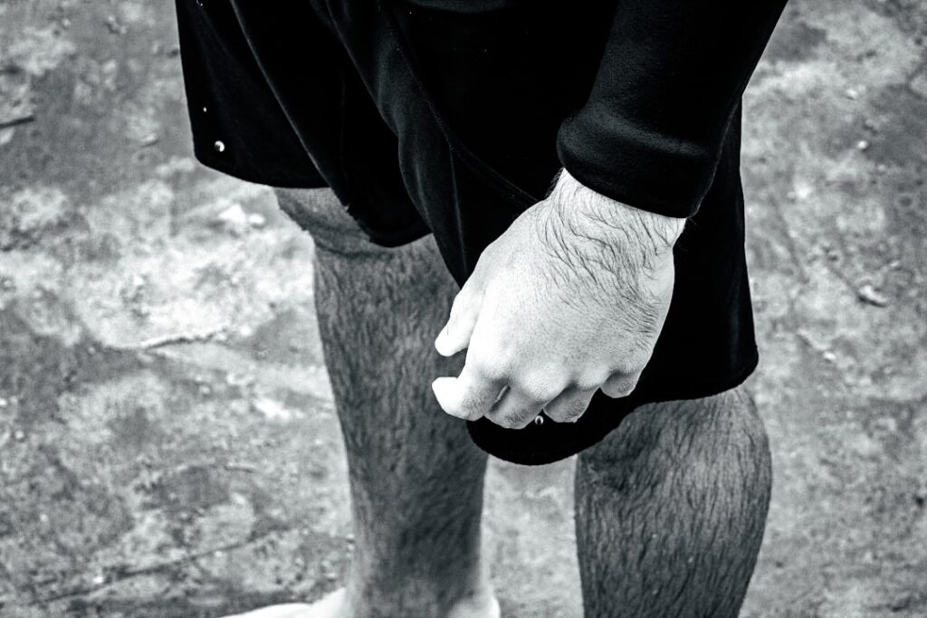 A person's legs and hand in black and white.