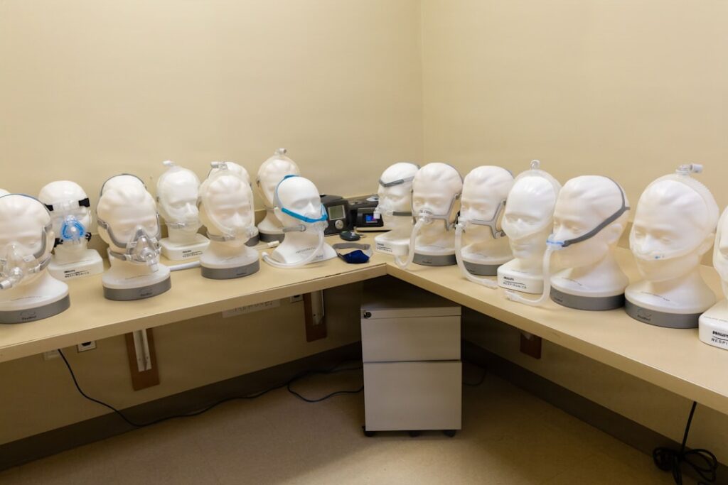 Many white mannequin heads with masks on display