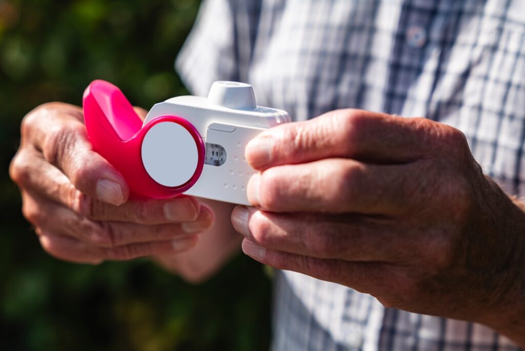 A man holding a camera with a pink object in his hand